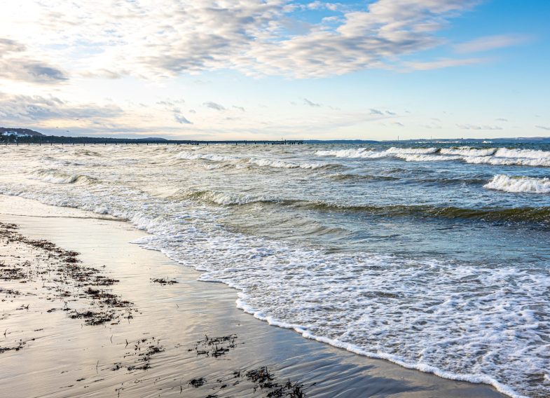 Beautiful seascape with clear blue sky, foamy waves on the sea.